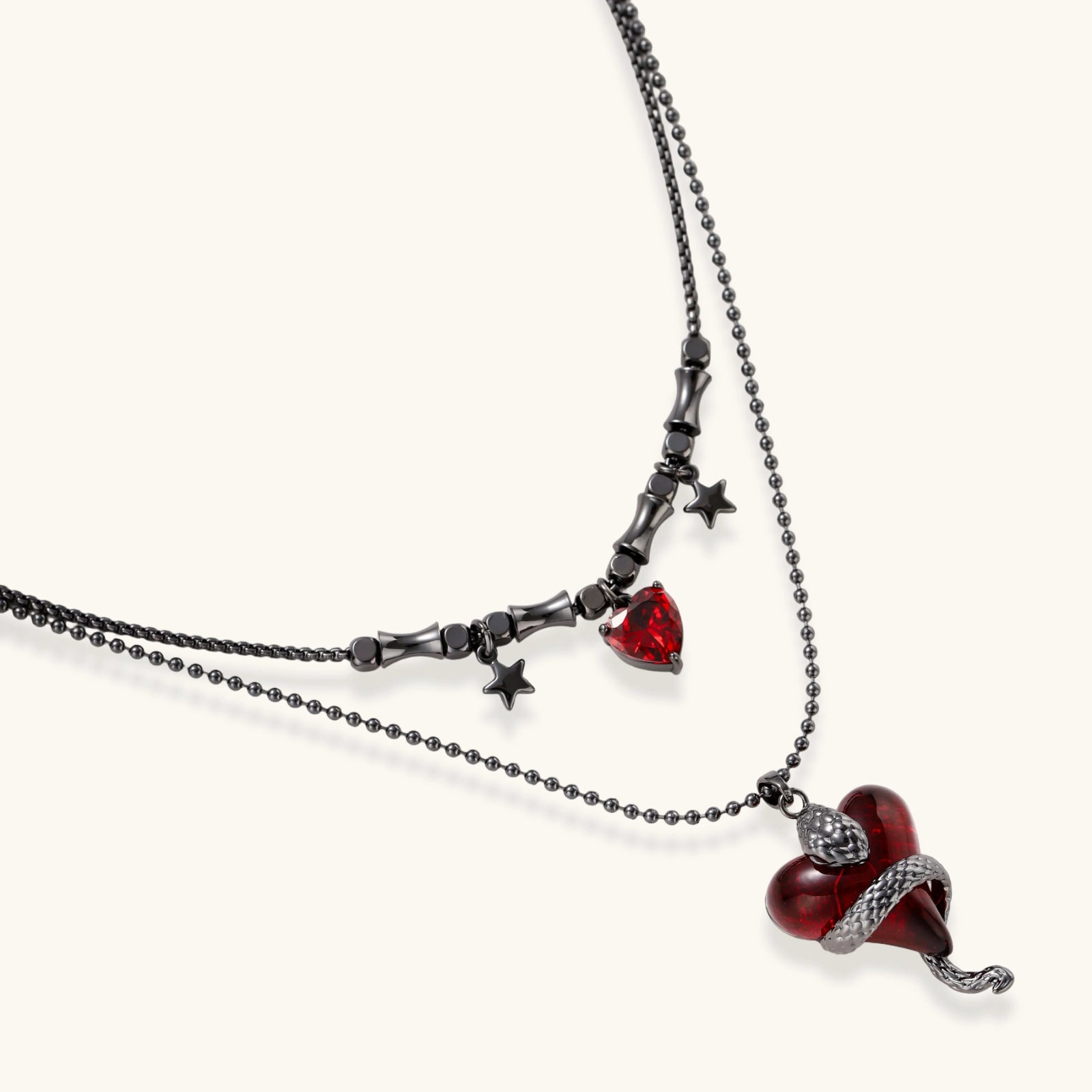 Dark layered necklace set with black chains and red heart pendants, featuring gothic snake design on white background