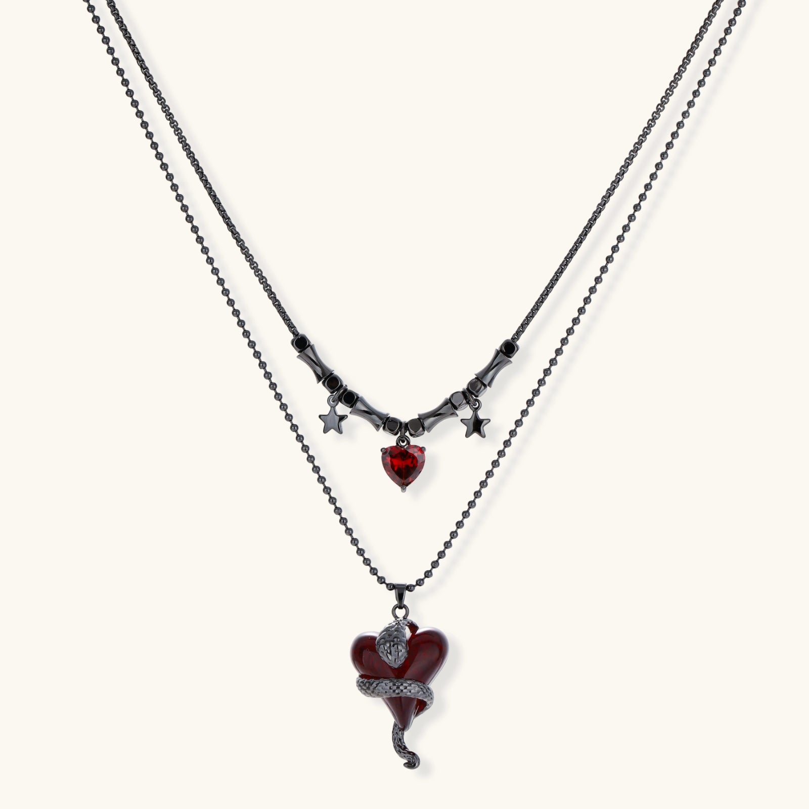 Dark layered necklace set with black chains and red heart pendants, featuring gothic snake design on white background