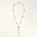 Gold-plated lariat necklace with baroque pearls and textured caps on cream background, showing adjustable Y-shaped design.