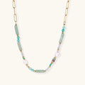 Gold chain necklace with seafoam green quartz cylinders, turquoise beads, and baroque pearl on cream background