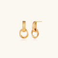Gold stud earrings with vertical ridged bar connecting to triple interlocking circular rings on white background