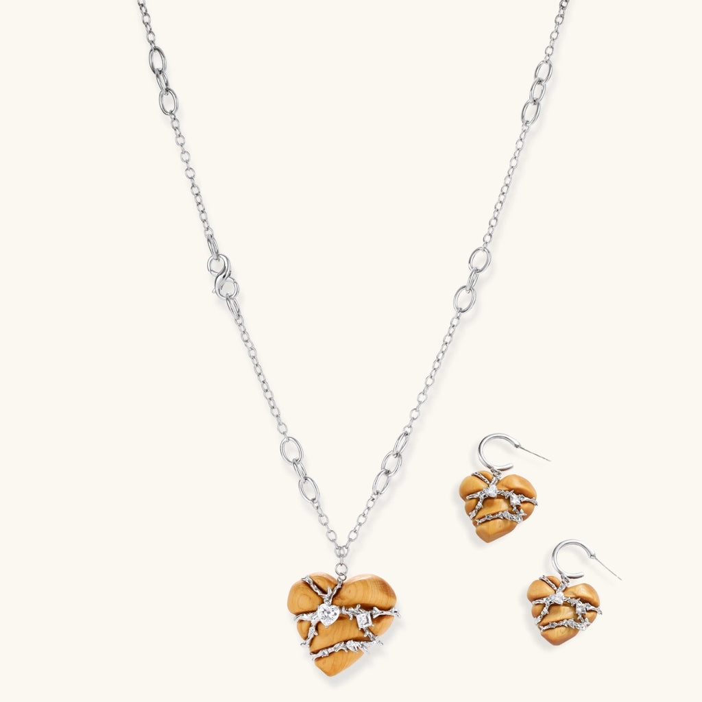 Heart-shaped eco-brass and wood jewelry set with silver wire detailing and crystal accents on cream background.